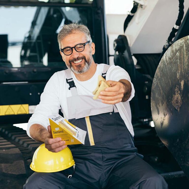 Lifestyle image of a construction worker, holding a Sammi Honey Gold Ham & Cheddar sandwich