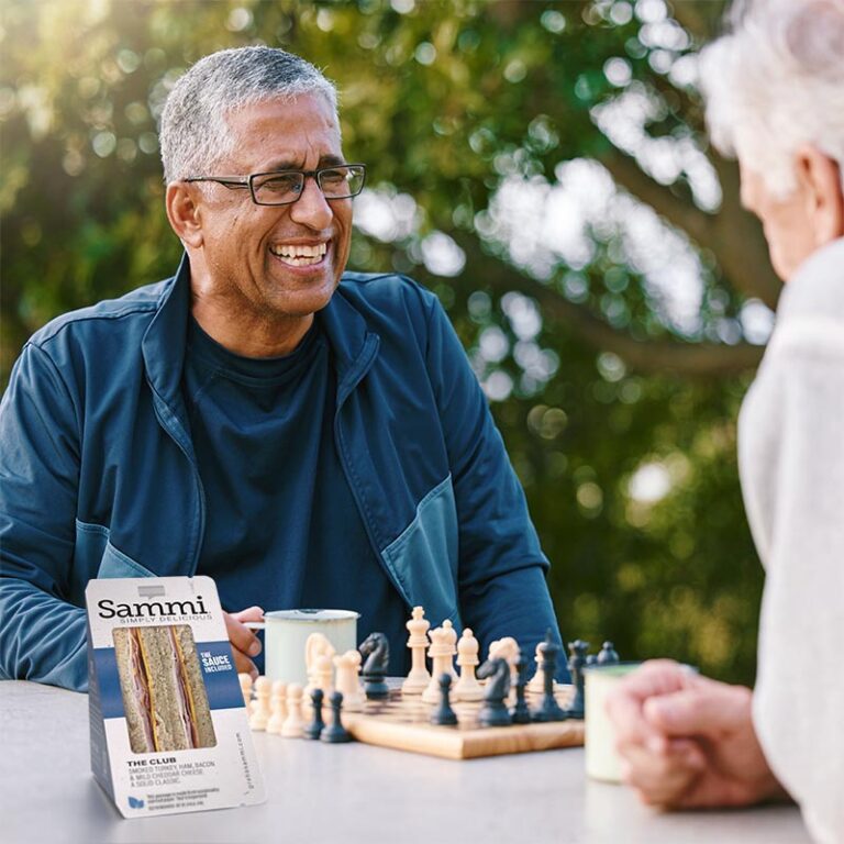 Image of gentleman playing chess in the park, Sammi Club Sandwich In foreground